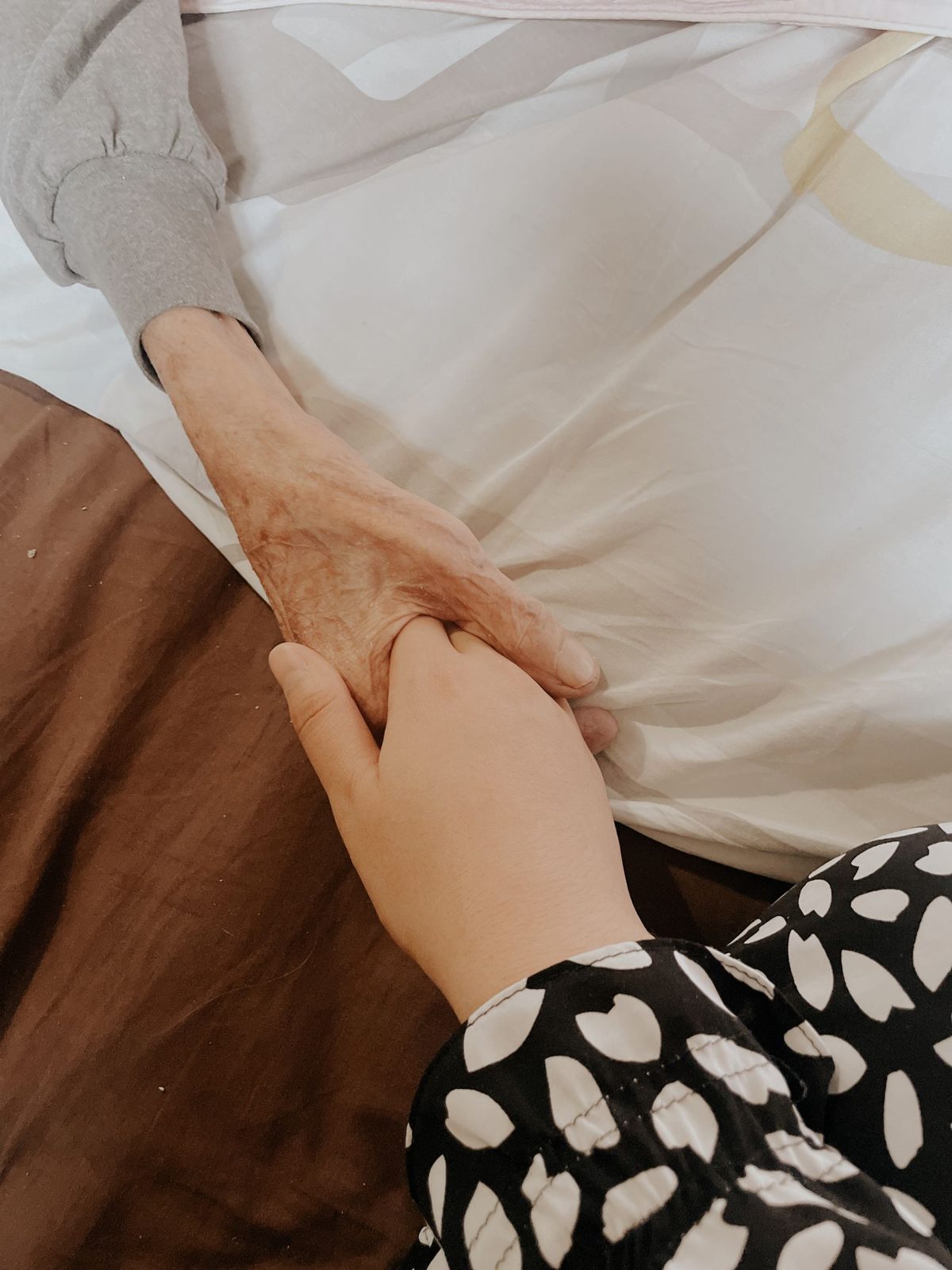 REACH Home Care caregiver holding the hand of an elderly client at home